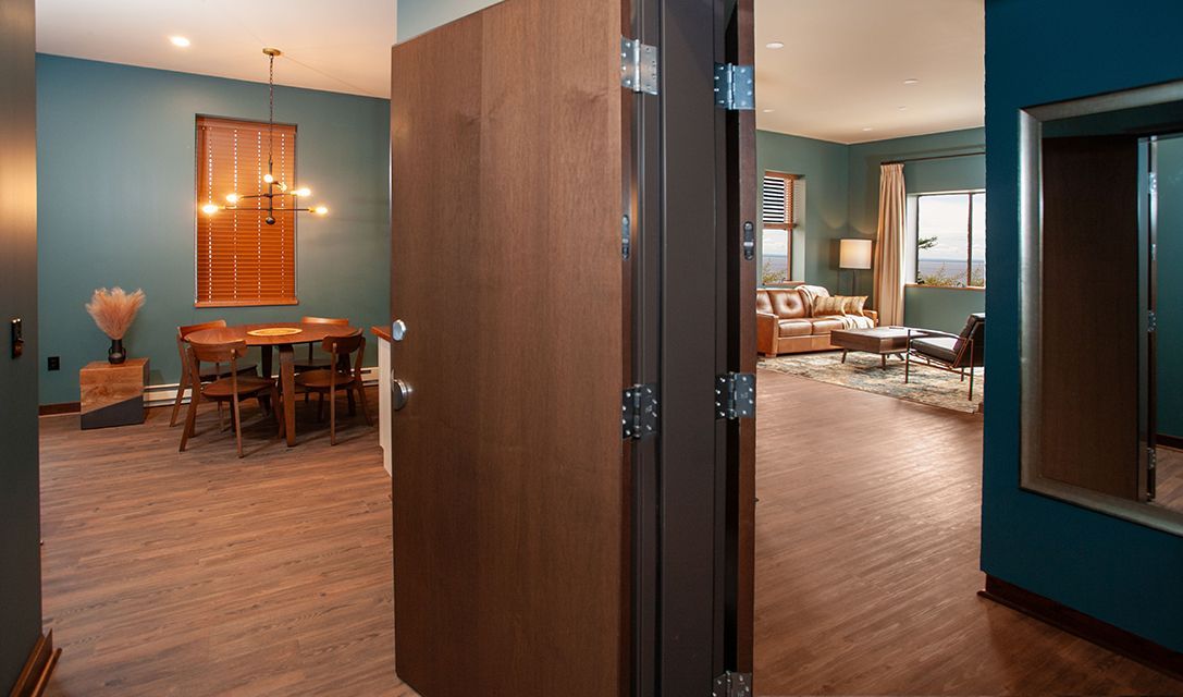 Open doorway between a blue dining room and a wood-floored living room with warm lighting