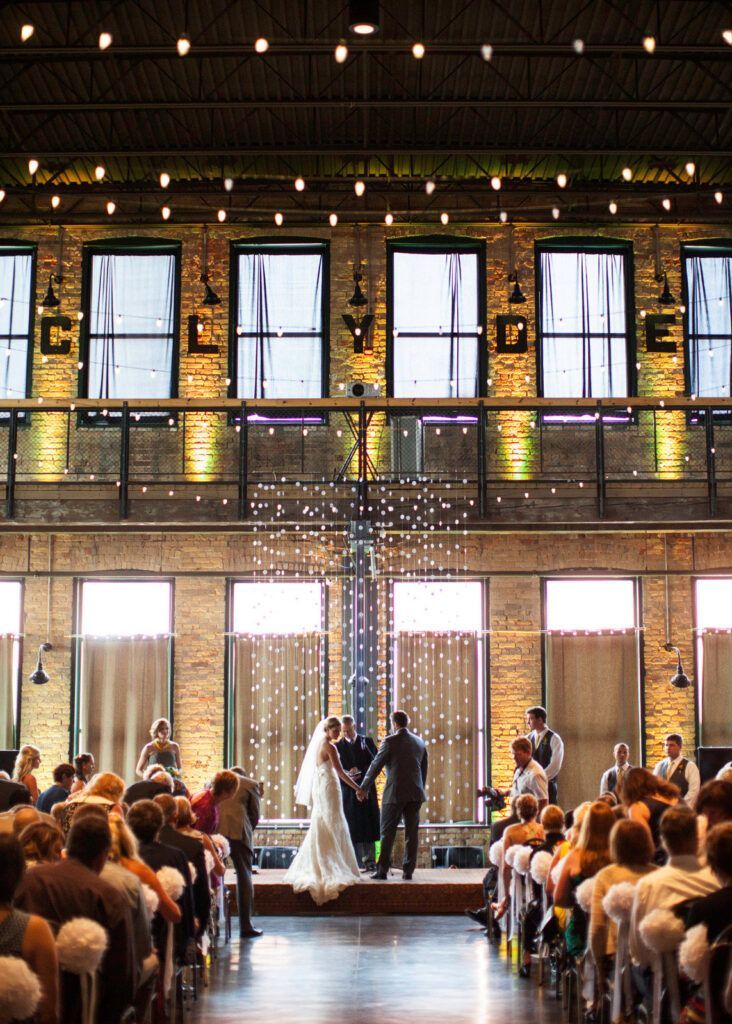 Wedding ceremony on a lit outdoor stage before seated guests at night