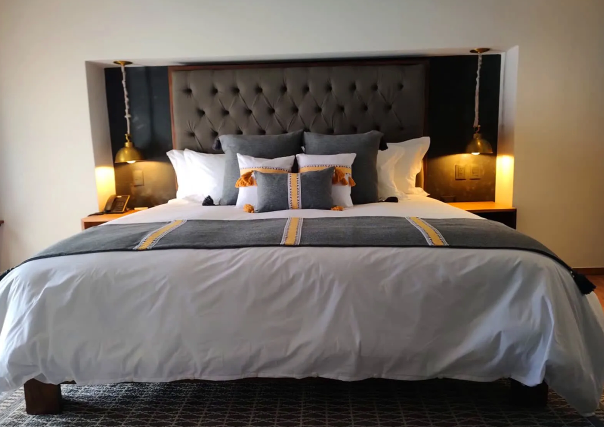 A bed with white sheets and pillows in a hotel room