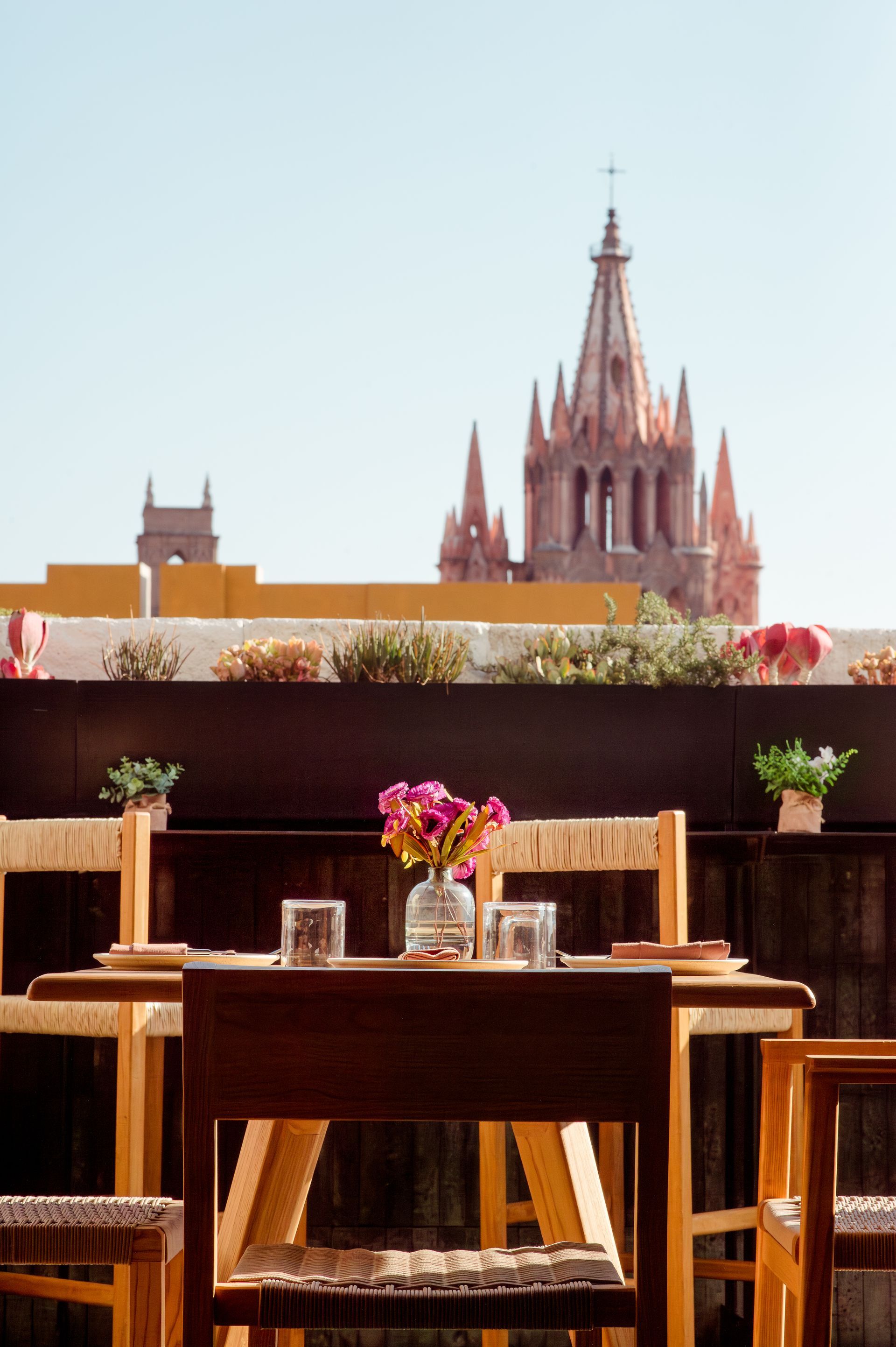 A table with a vase of flowers on it and a cathedral in the background