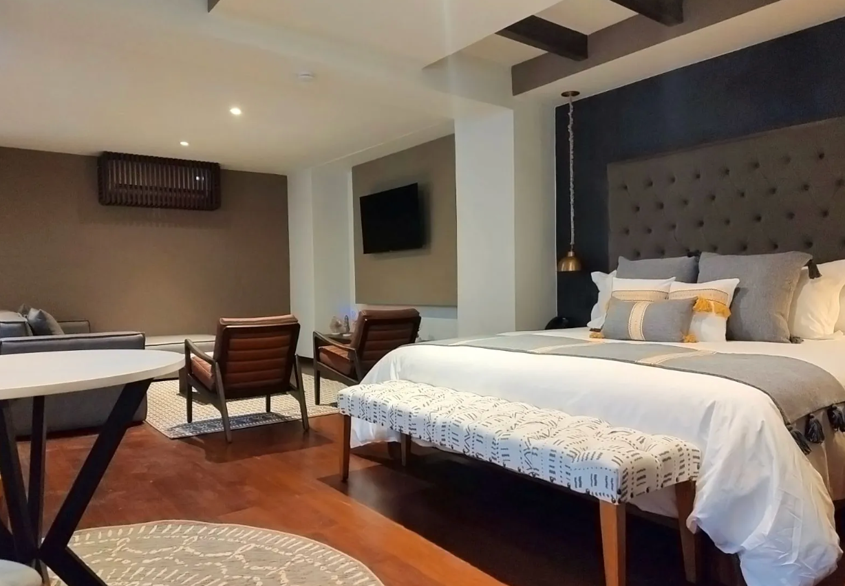 A bedroom with a king size bed , chairs , a table and a television.