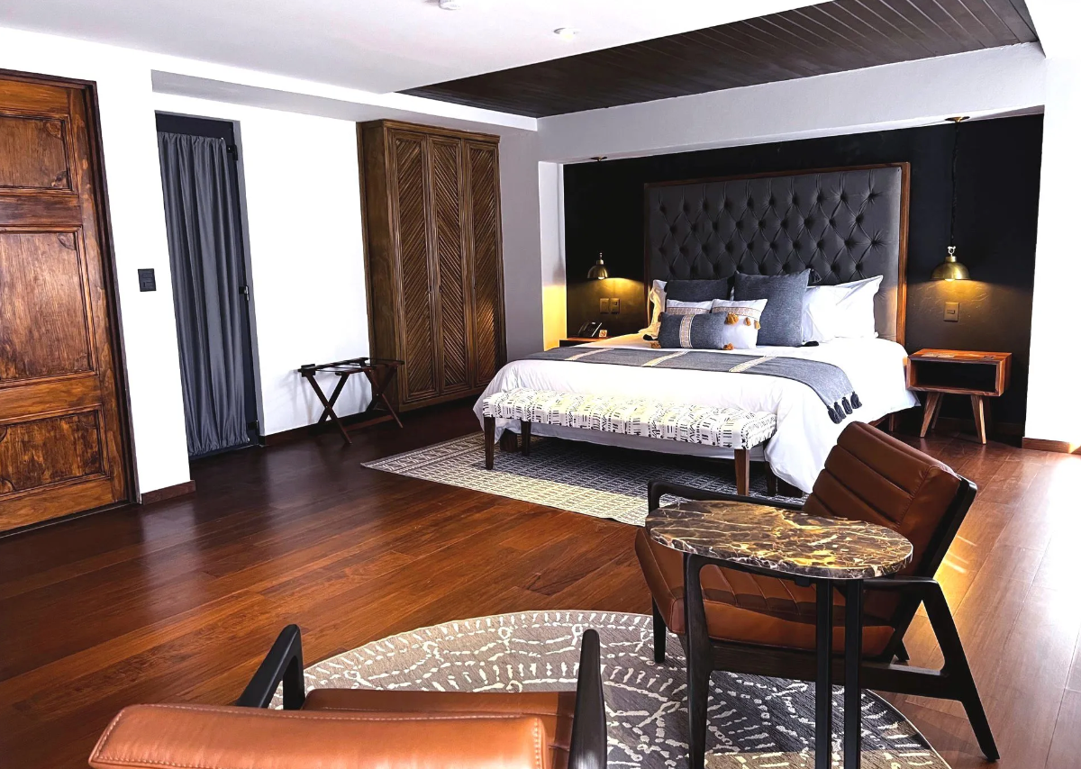 A hotel room with a bed , chairs , table and rug.