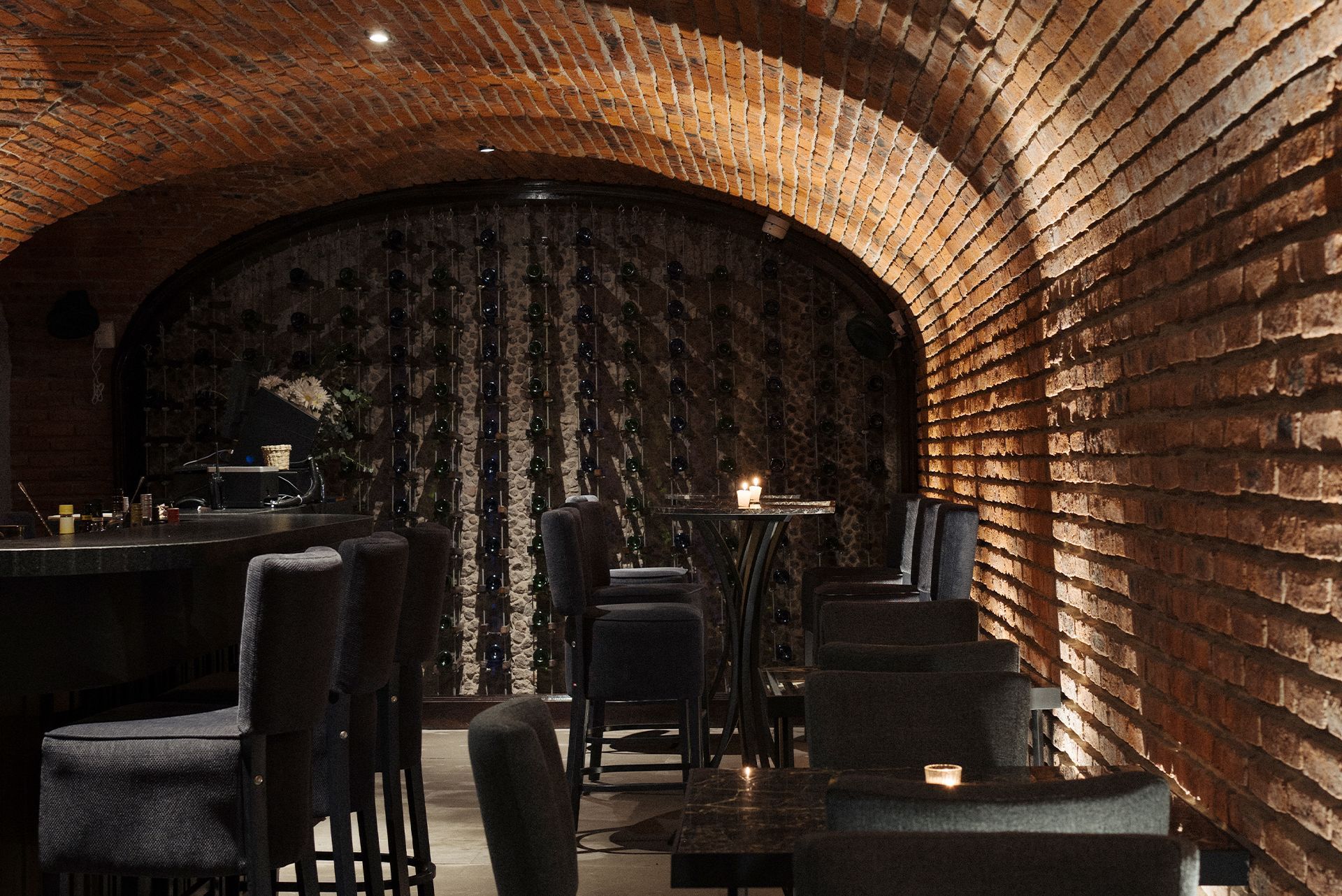 A dark room with a brick wall and tables and chairs