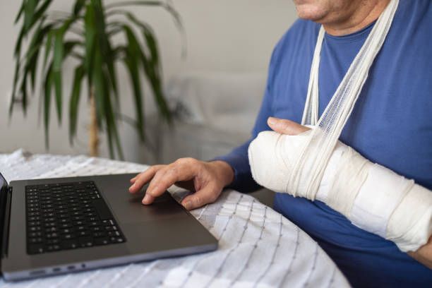 Injury Attorney assisting client with arm cast via laptop for legal consultation at home