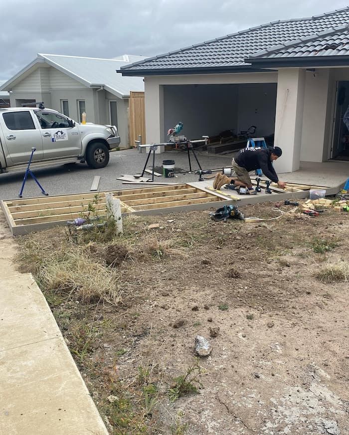 A Man Is Working on A Wooden Deck in Front of A House — Flintoff Constructions in Charlemont, VIC
