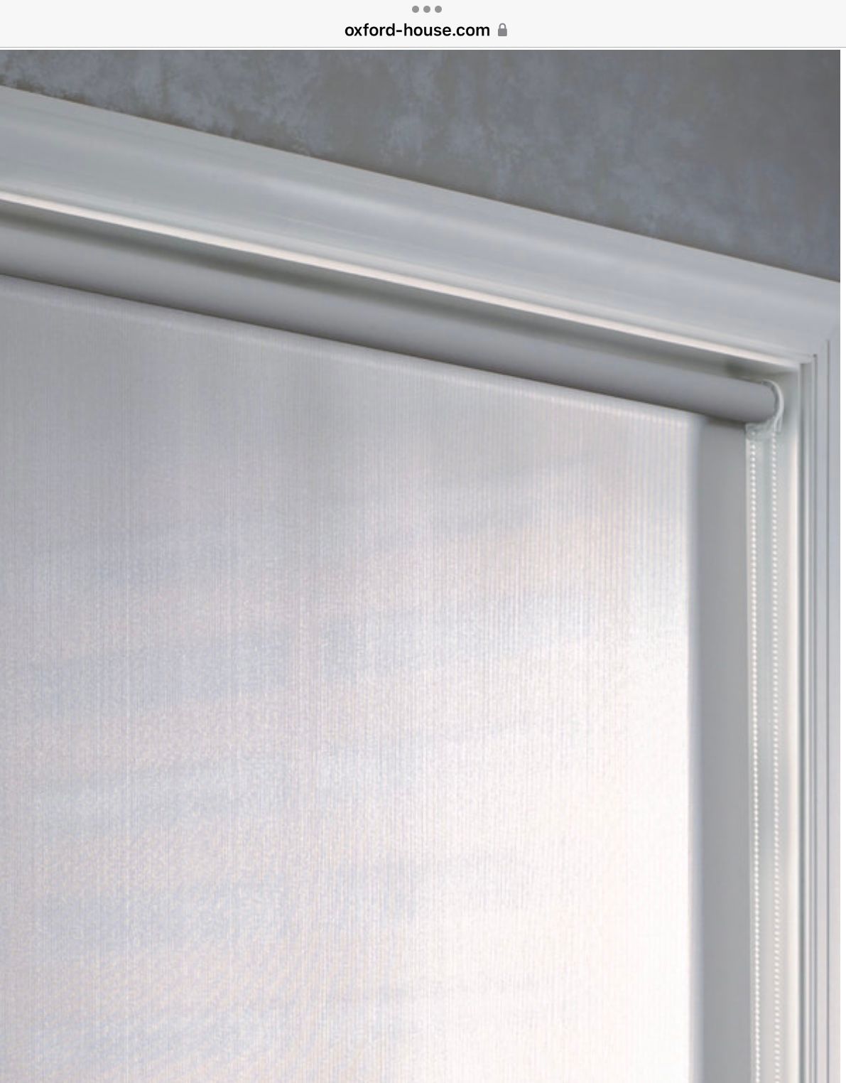 A close-up view of a white roller blind mounted inside a white window frame.