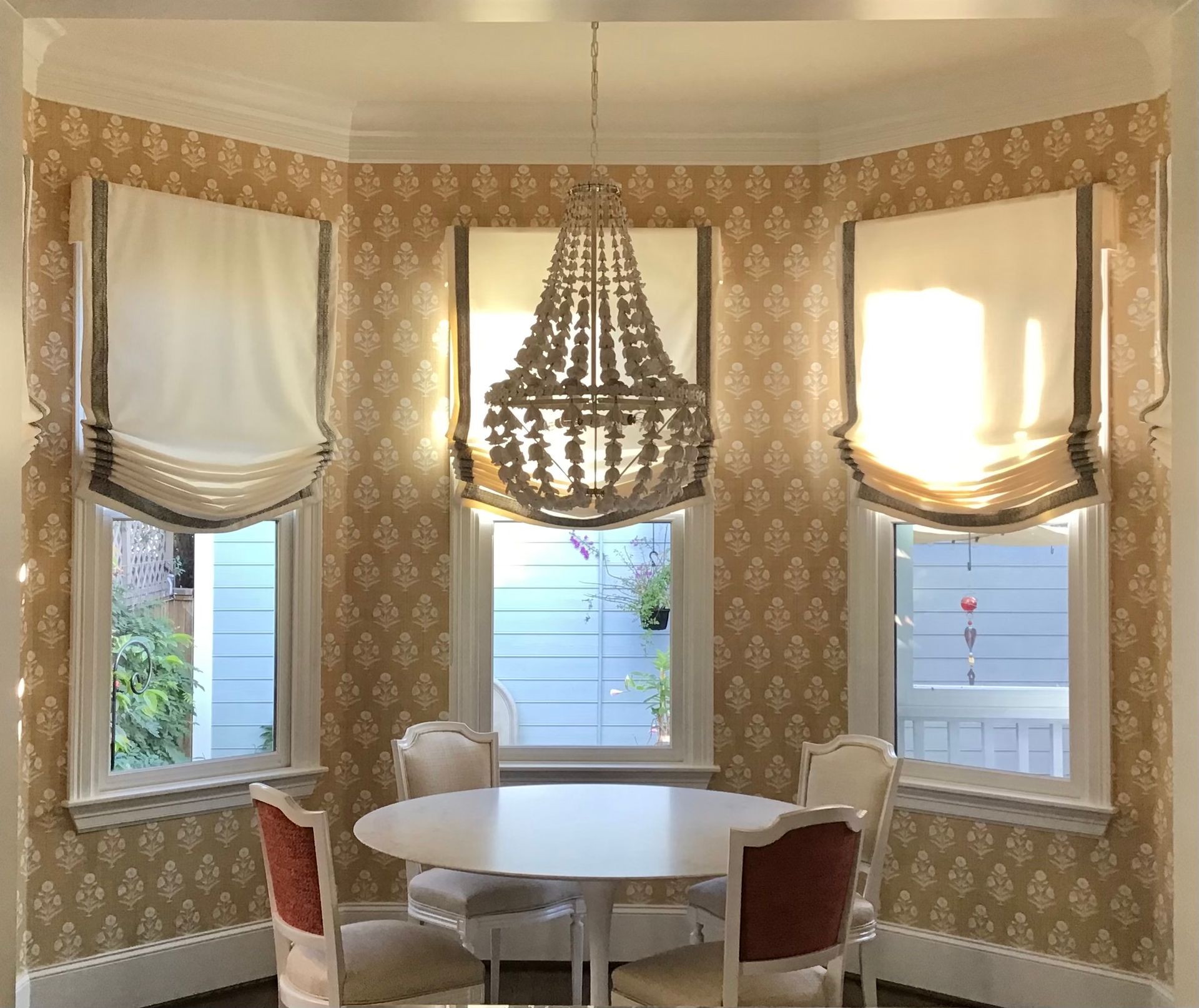 Dining room with windows, floral curtains, chandelier, artwork, and table setting.