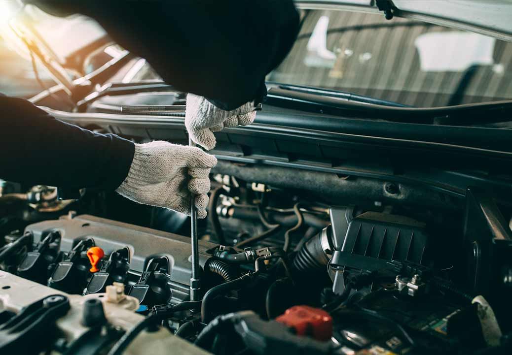 Mechanic working on car brake system with a wrench, focusing on the rotor, in a garage setting.