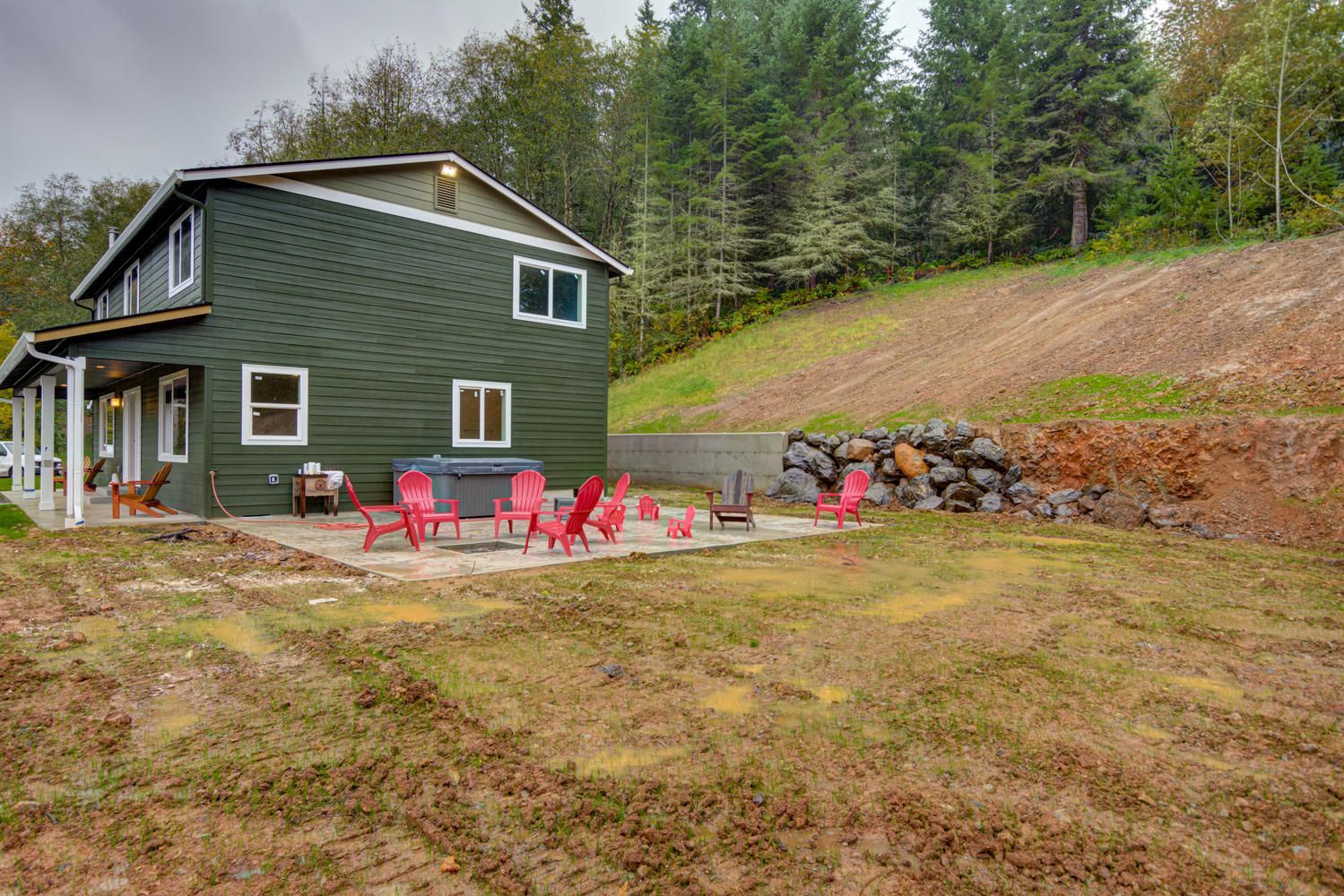 A green house with red chairs and a fire pit in front of it.