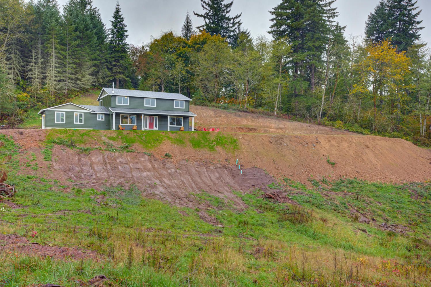 A house is sitting on top of a hill surrounded by trees.