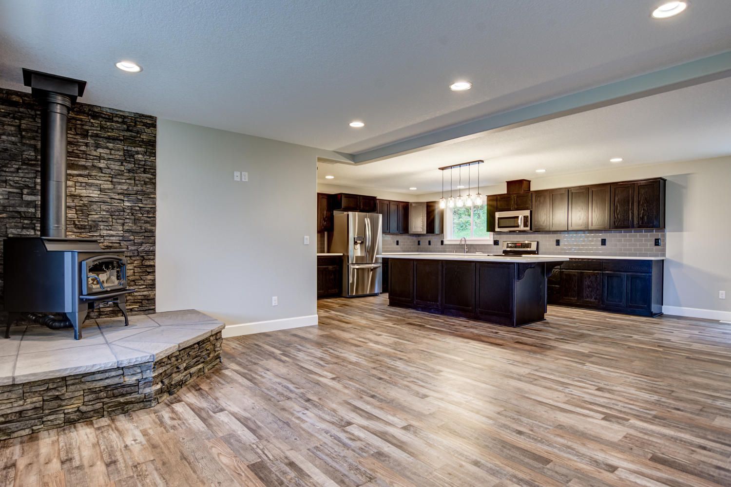 A large empty kitchen with hardwood floors and a wood stove.