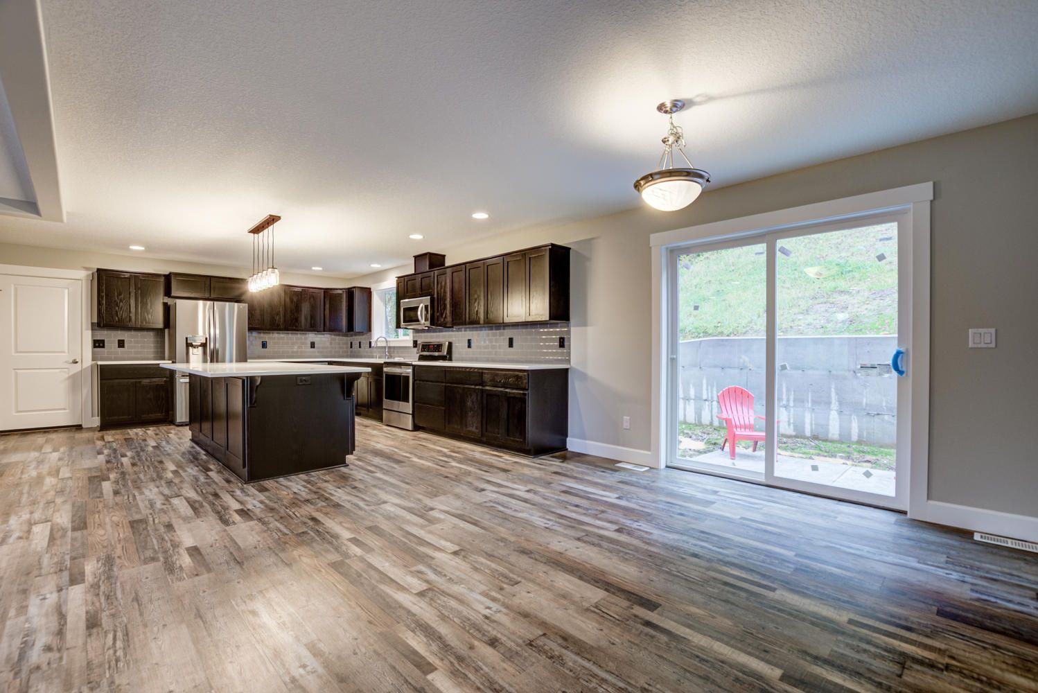 A large empty kitchen with sliding glass doors and hardwood floors.