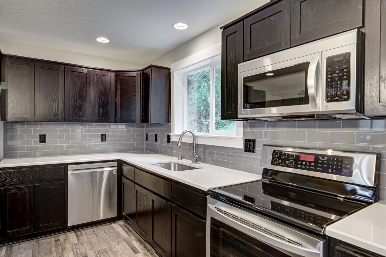 A kitchen with stainless steel appliances and black cabinets.