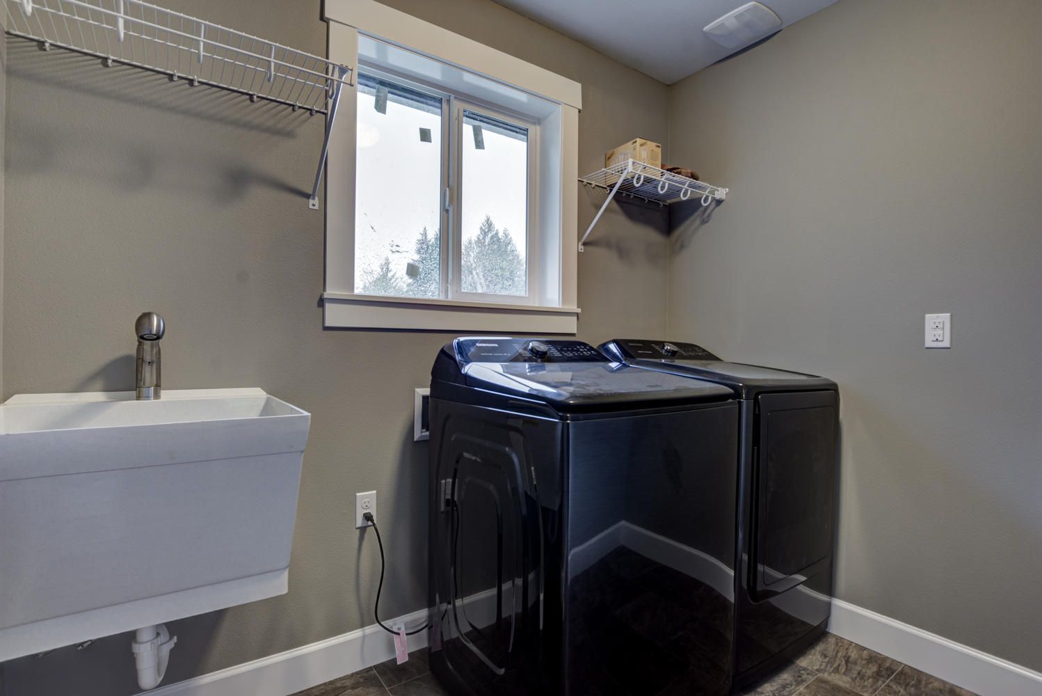 A laundry room with a sink , washer and dryer , and a window.