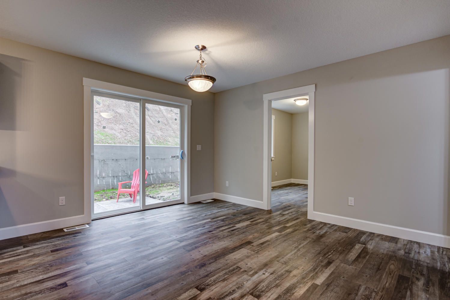 An empty living room with hardwood floors and sliding glass doors.