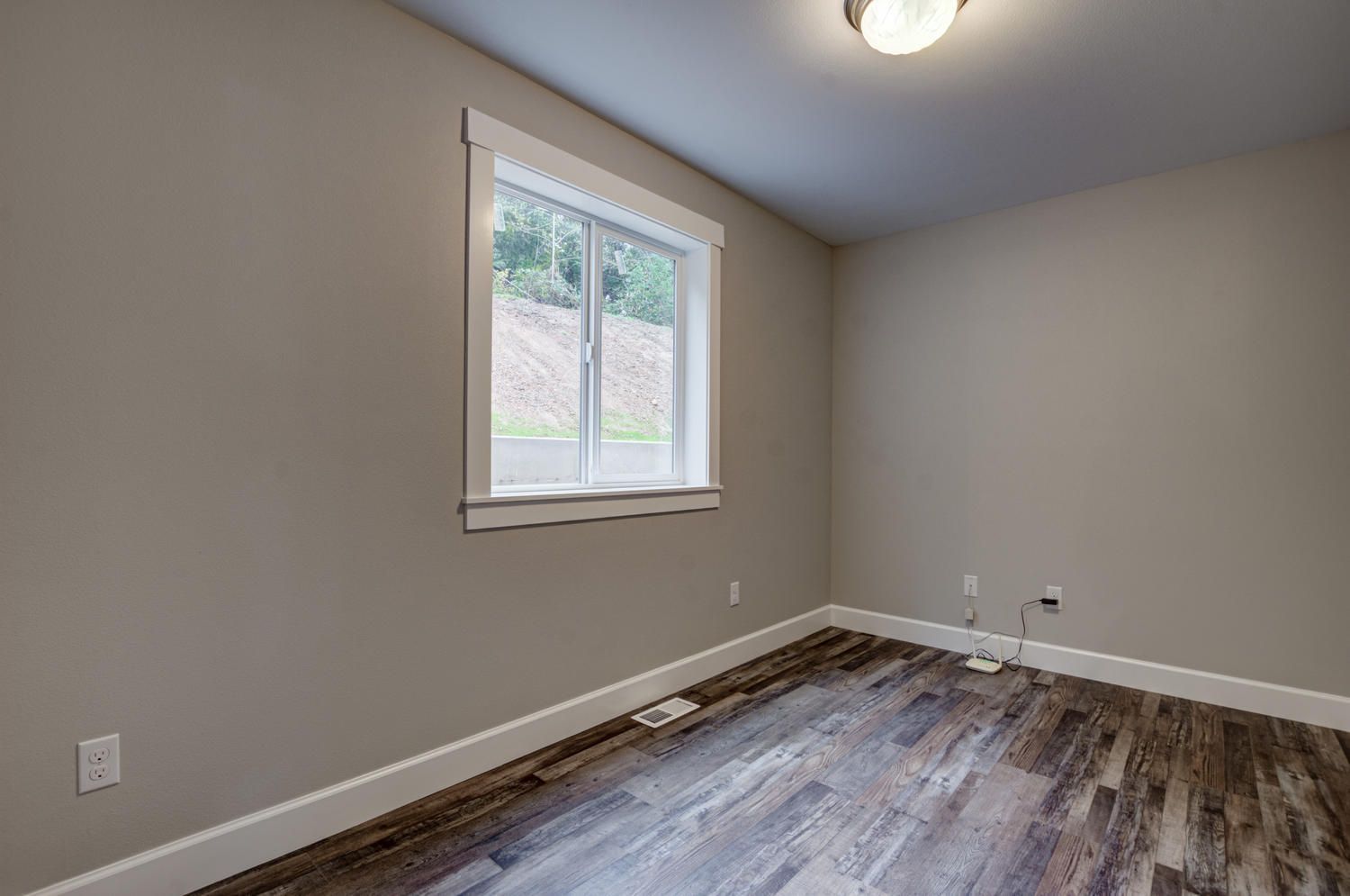 An empty room with hardwood floors and a window.