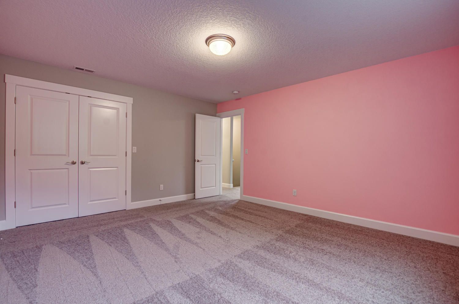 An empty bedroom with pink walls and a pink carpet.