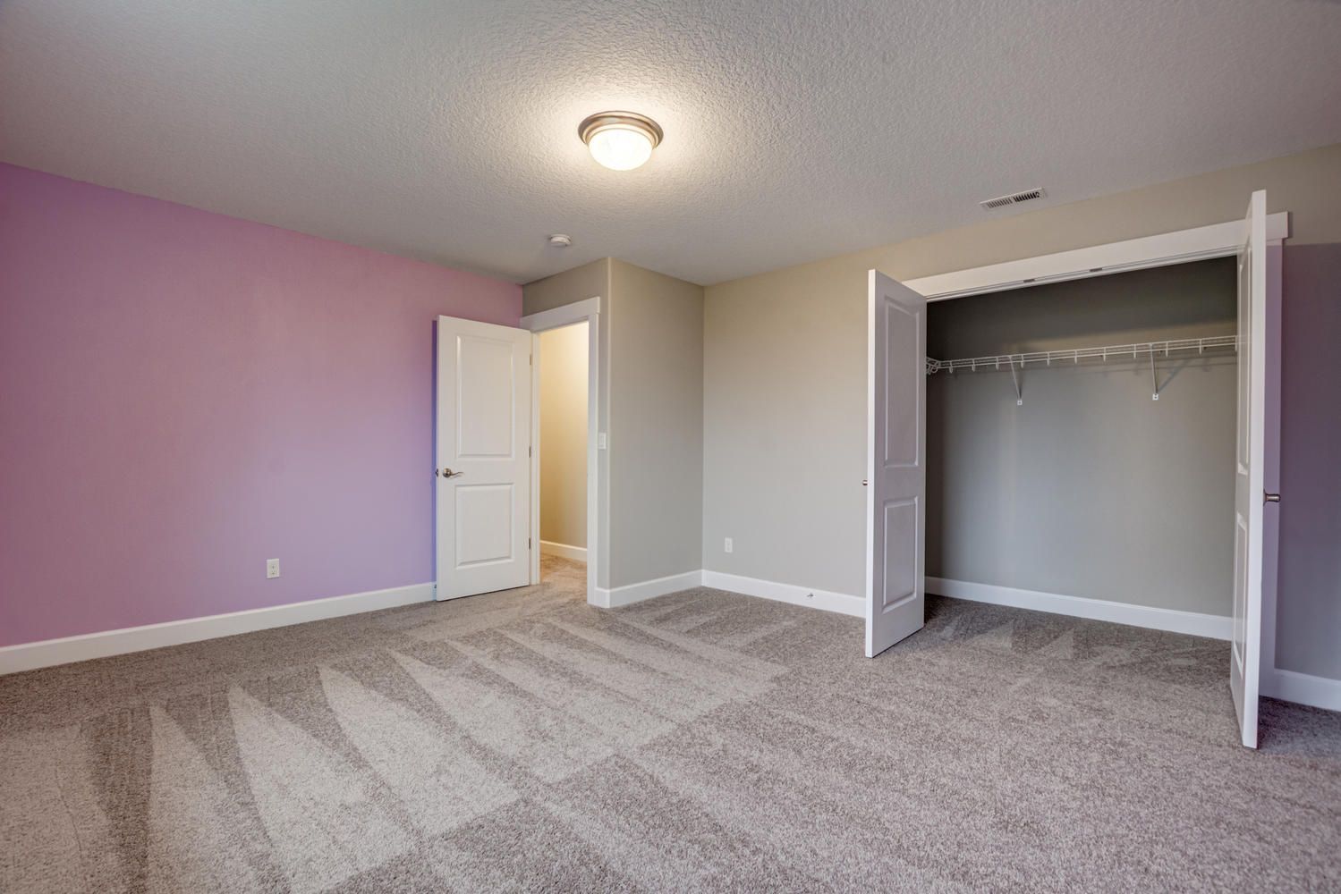 An empty bedroom with pink walls and a closet.