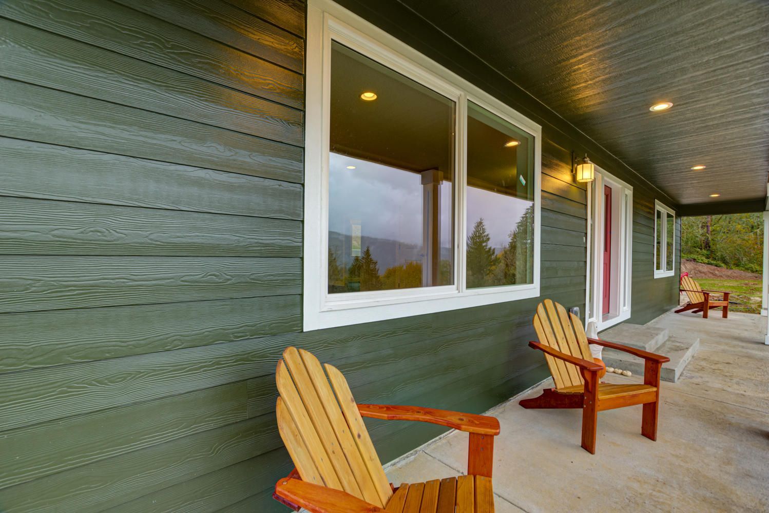 There are two chairs on the porch of a house.