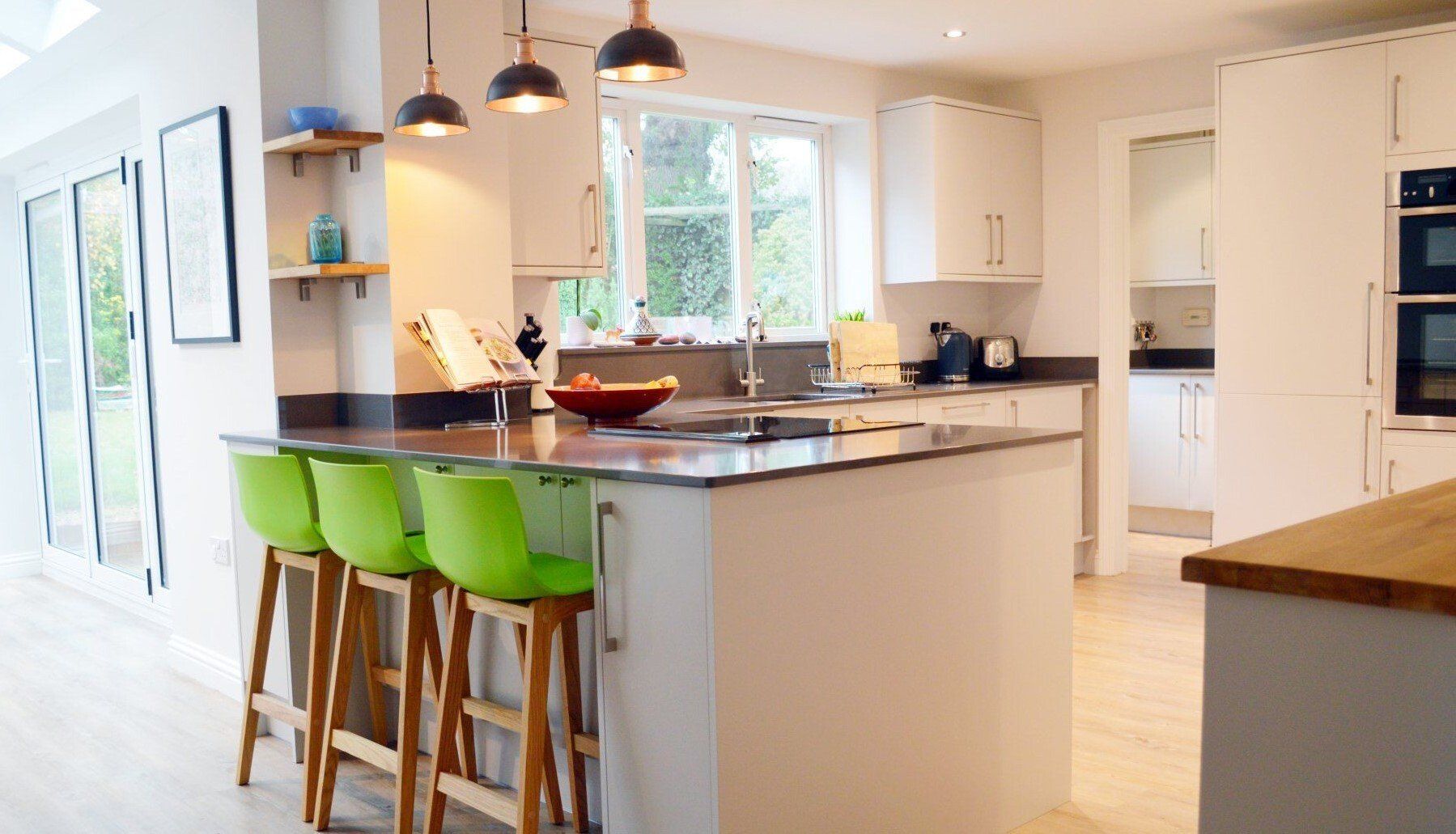 modern white kitchen with lime green chairs and hanging pendant lamps