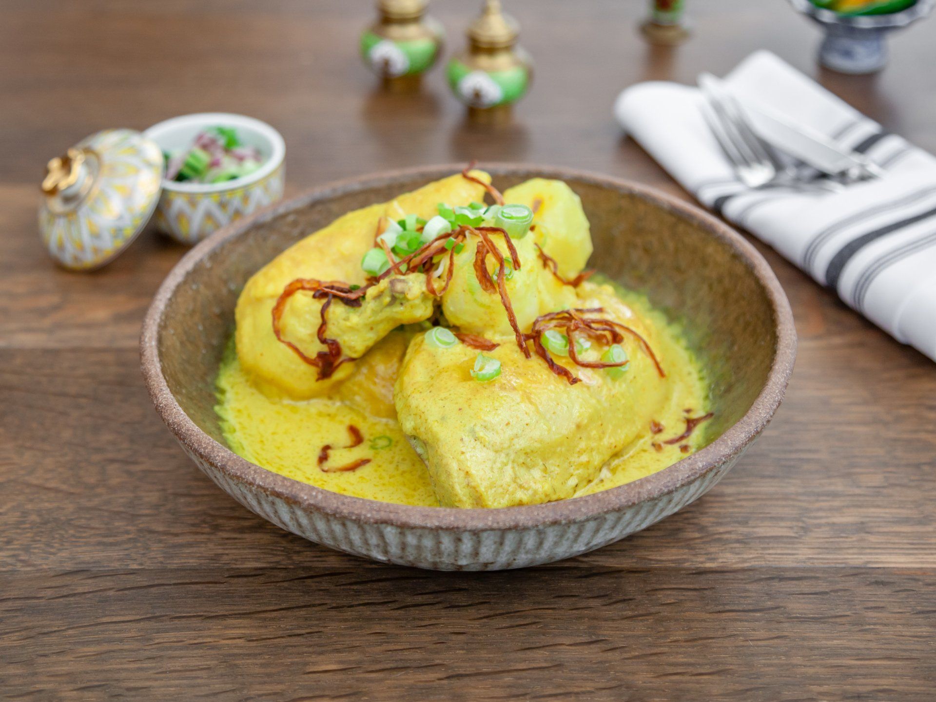 Half chicken simmered in yellow curry with potatoes, topped with fried shallots.