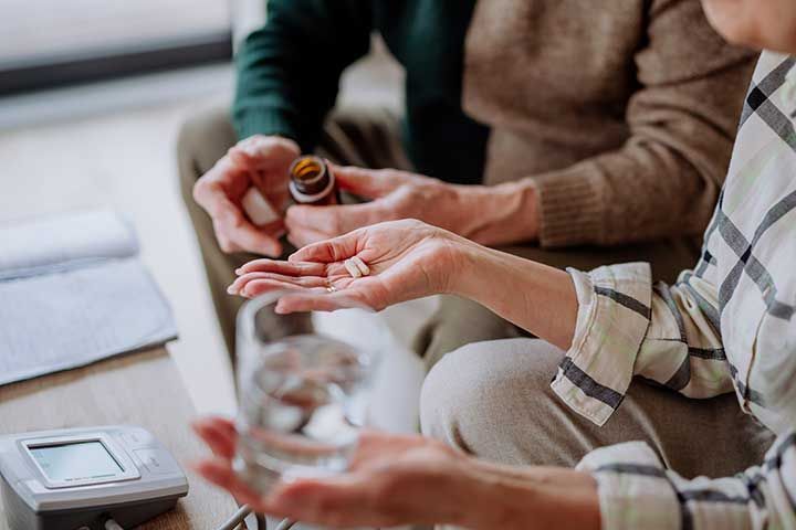 Close-up of senior man giving his wife medication at home 
