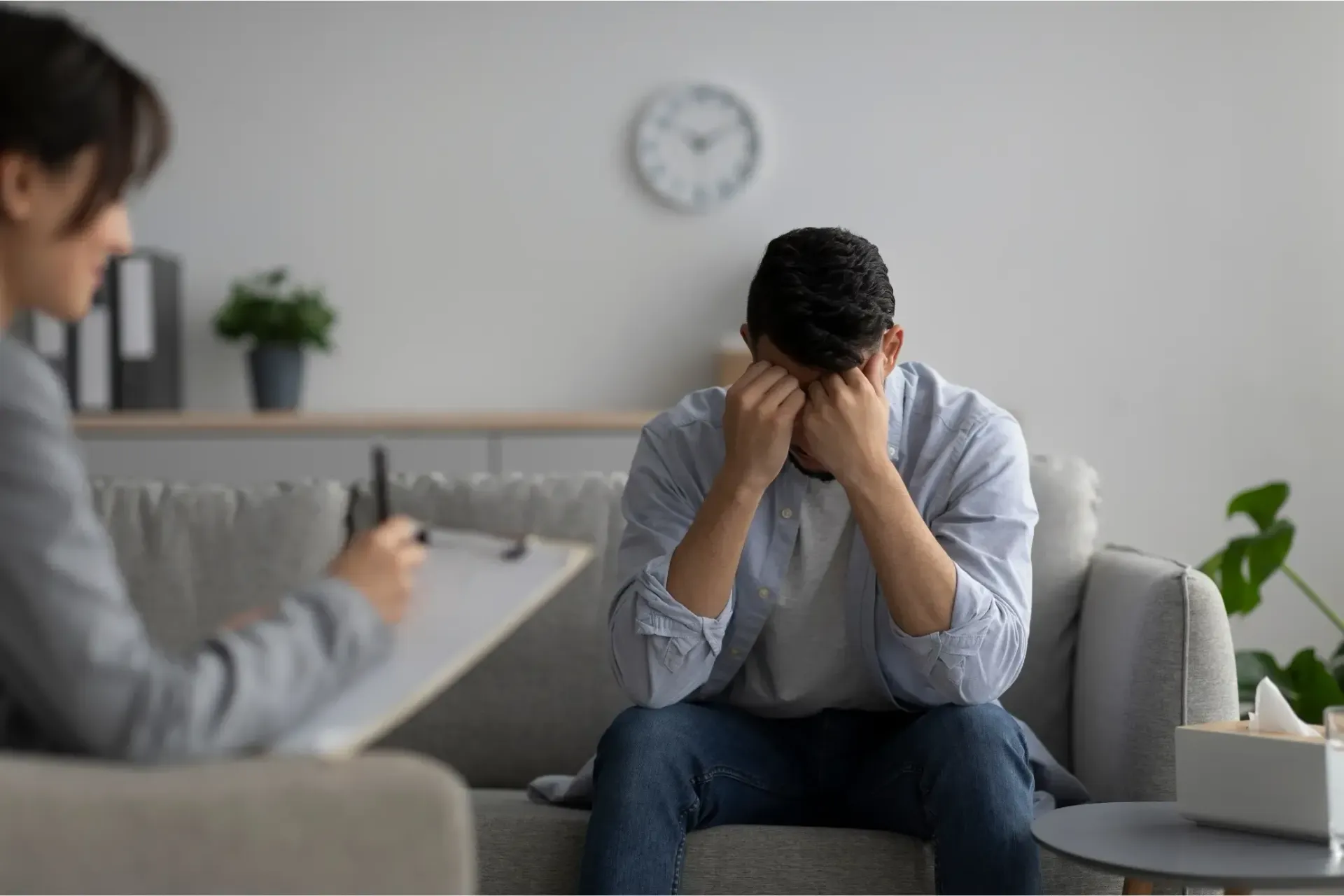 Man with head in hands on couch in therapy session