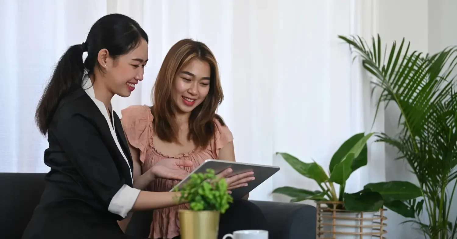 Two women looking at a tablet, smiling.