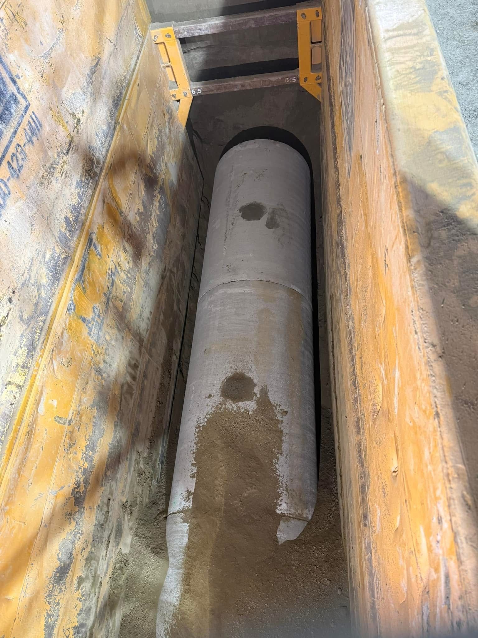Concrete pipe installation inside a utility vault for stormwater or wastewater infrastructure.