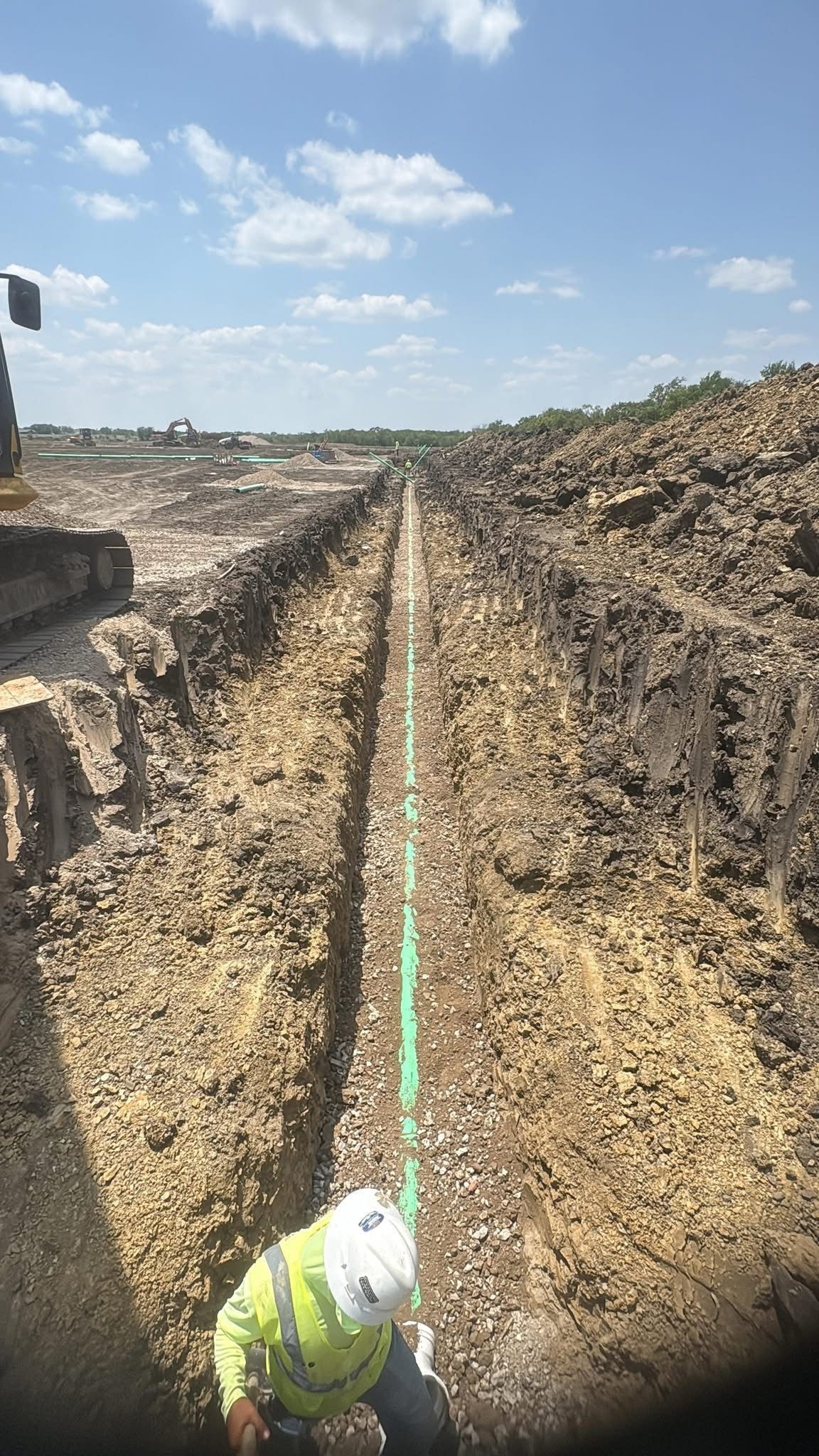 Wide construction site with excavation and grading underway under a clear sky.