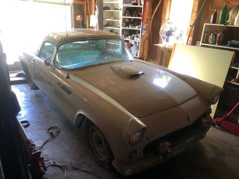 An old white car is parked in a garage.