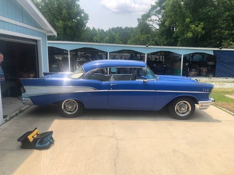 A blue car is parked in a driveway next to a garage.