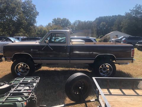 A truck is parked next to a trailer in a field.