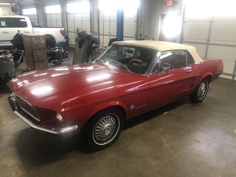 A red mustang convertible is parked in a garage.