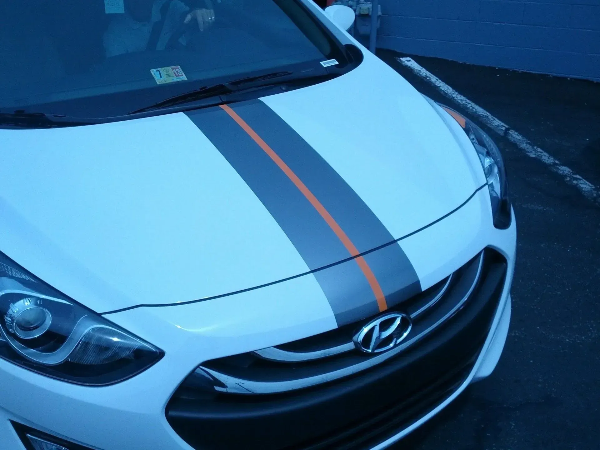 A white car with black and orange stripes on the hood.