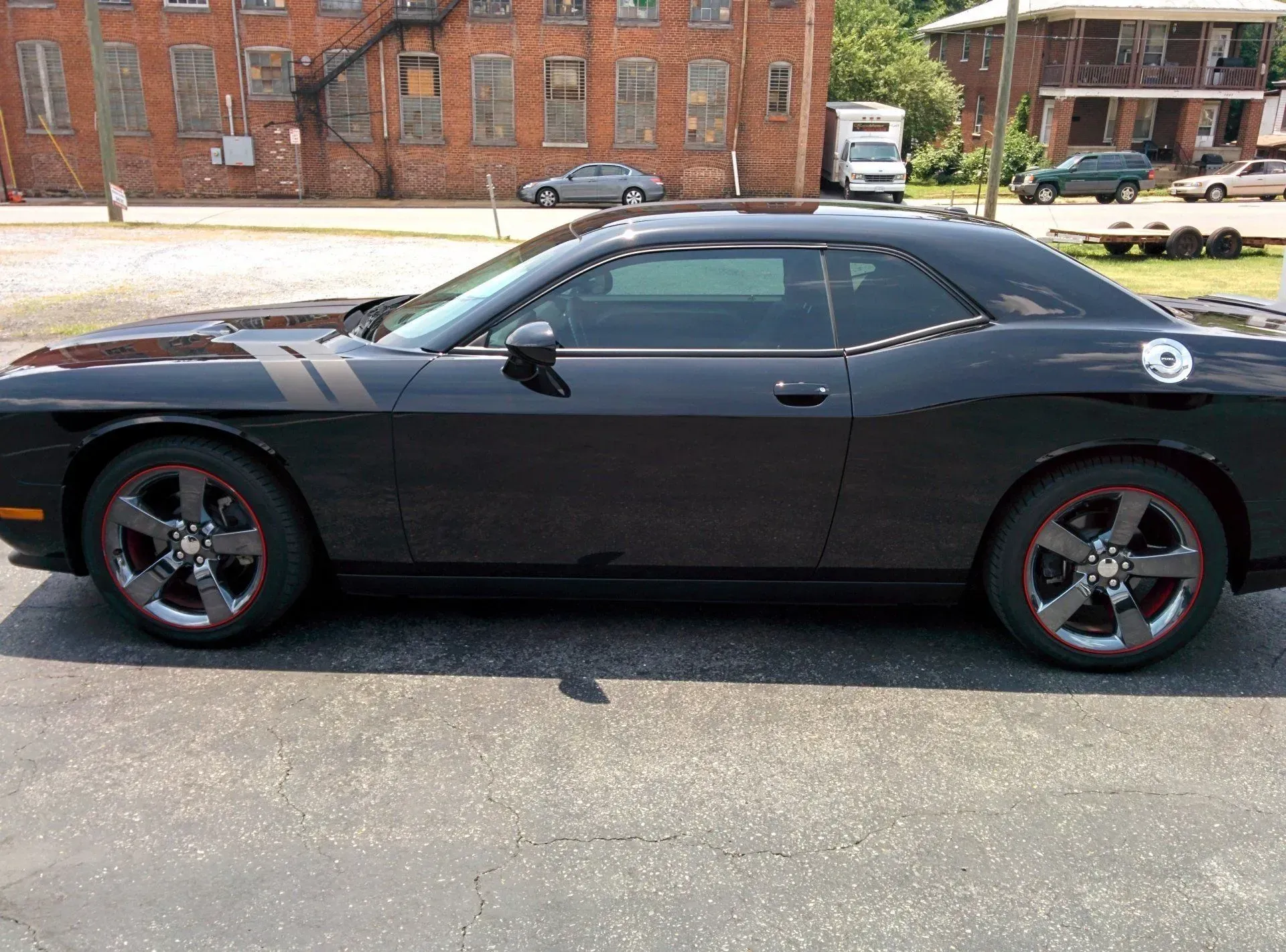 A black dodge challenger is parked in a parking lot.
