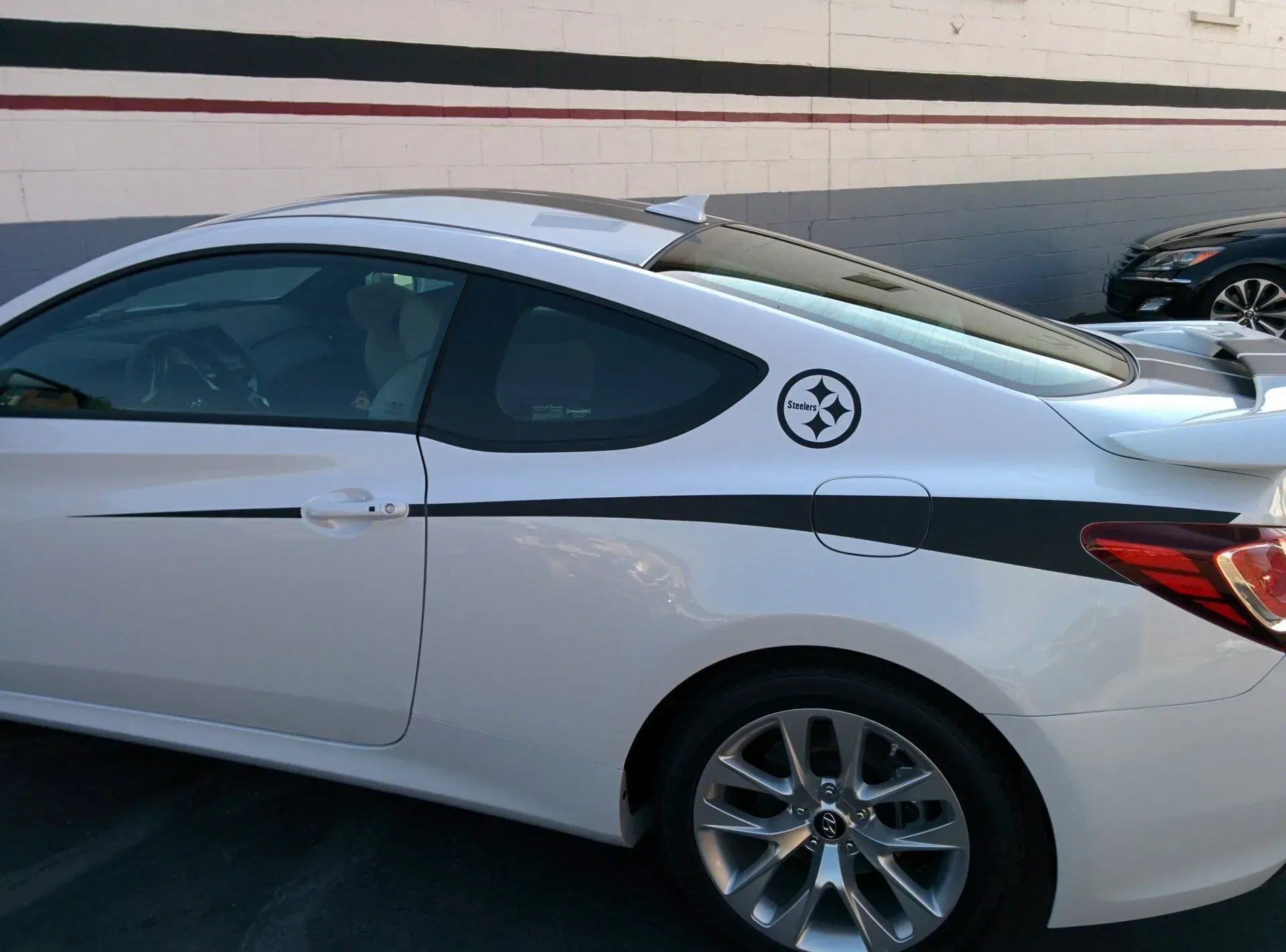 A white car with a black stripe on the side is parked in a parking lot.