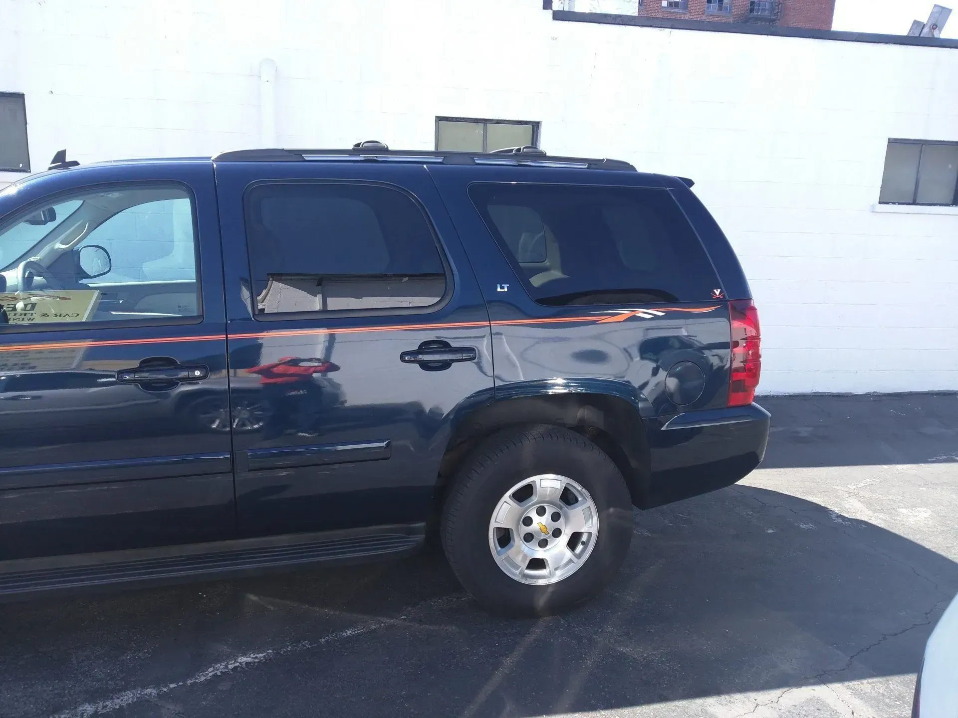 A blue suv is parked in front of a white building.