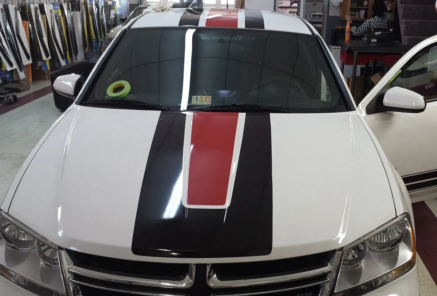 A white car with a red and black stripe on the hood.