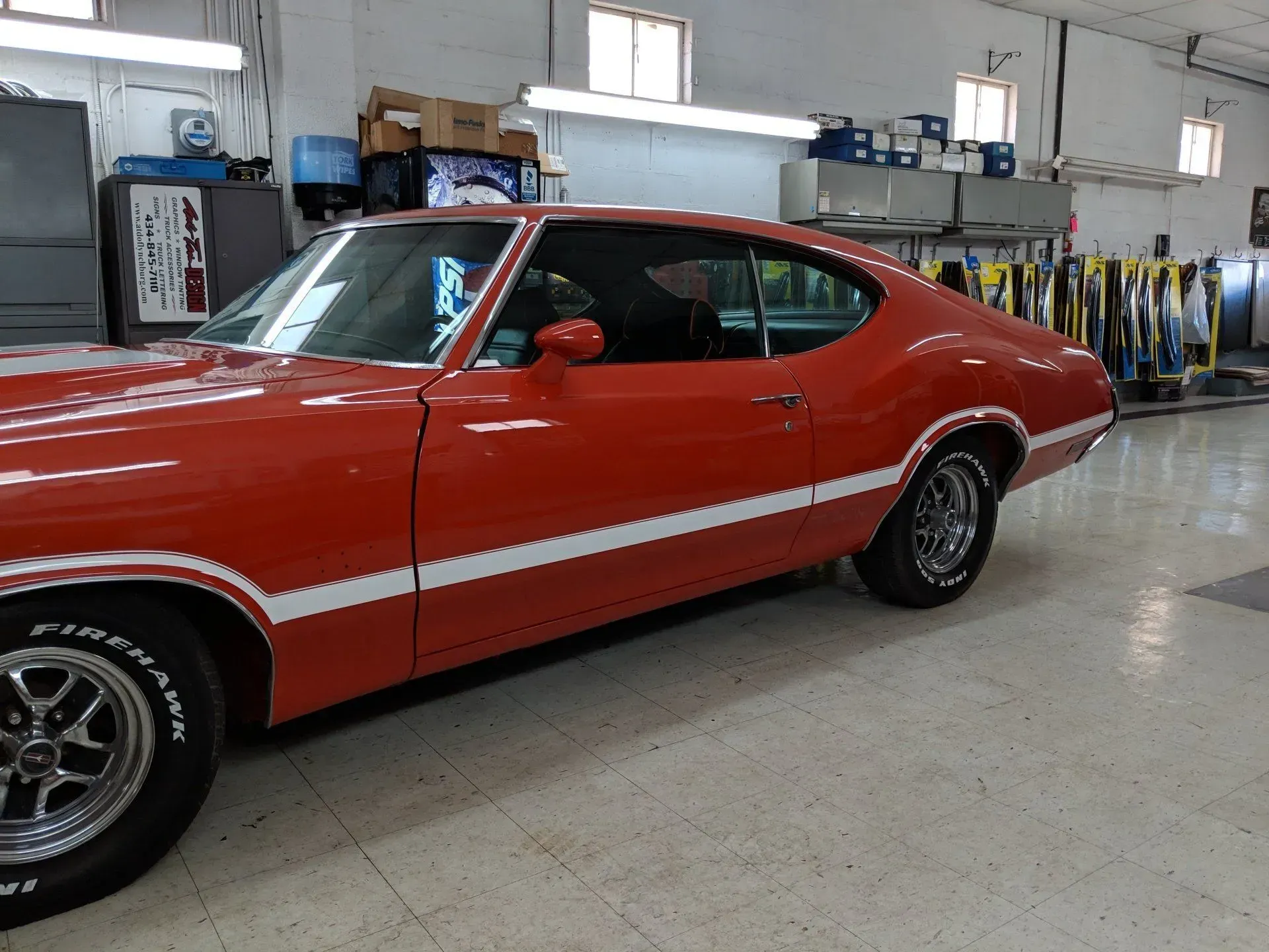 A red car with bfgoodrich tires is parked in a garage.
