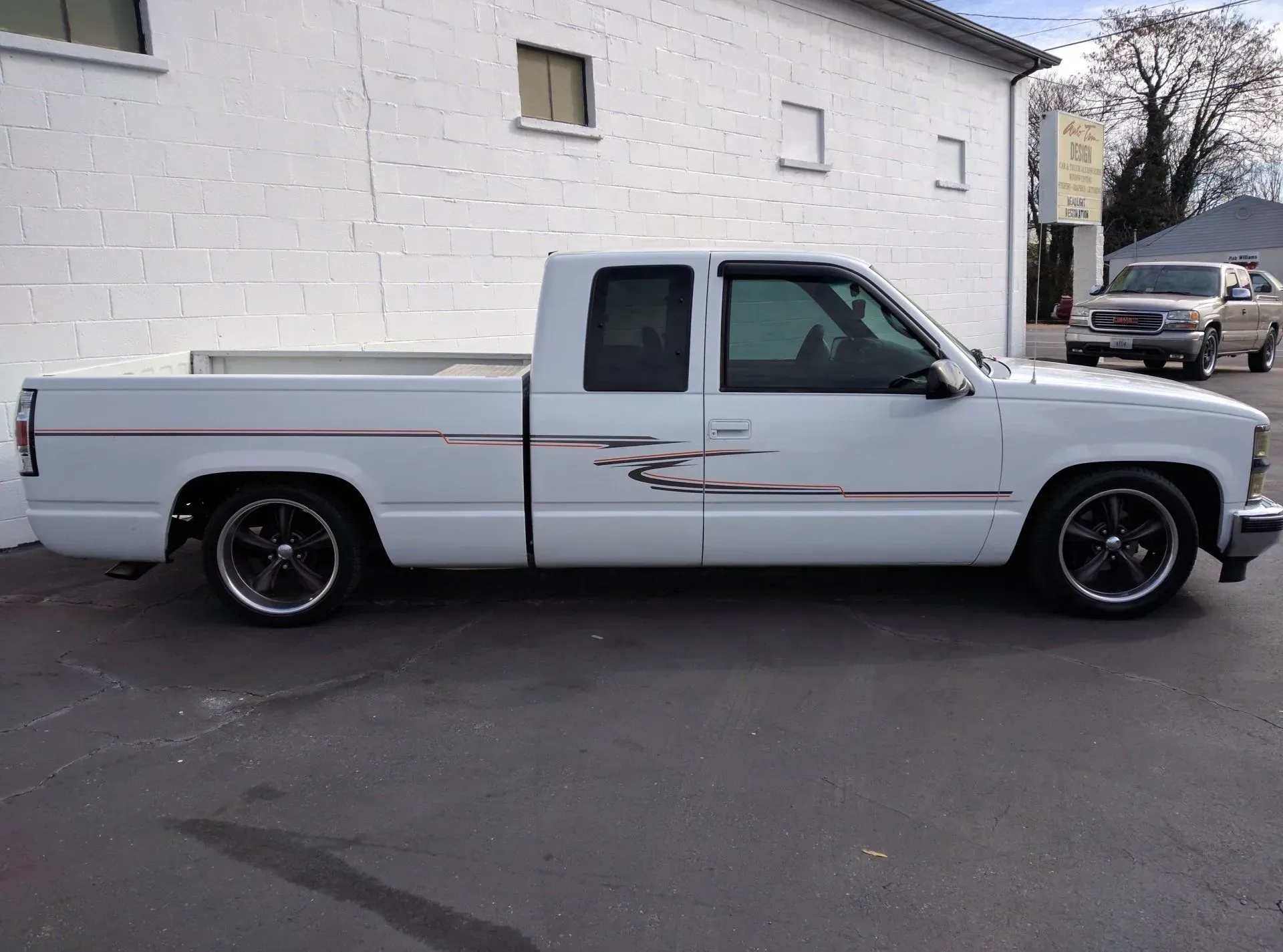 A white truck is parked in front of a white building.