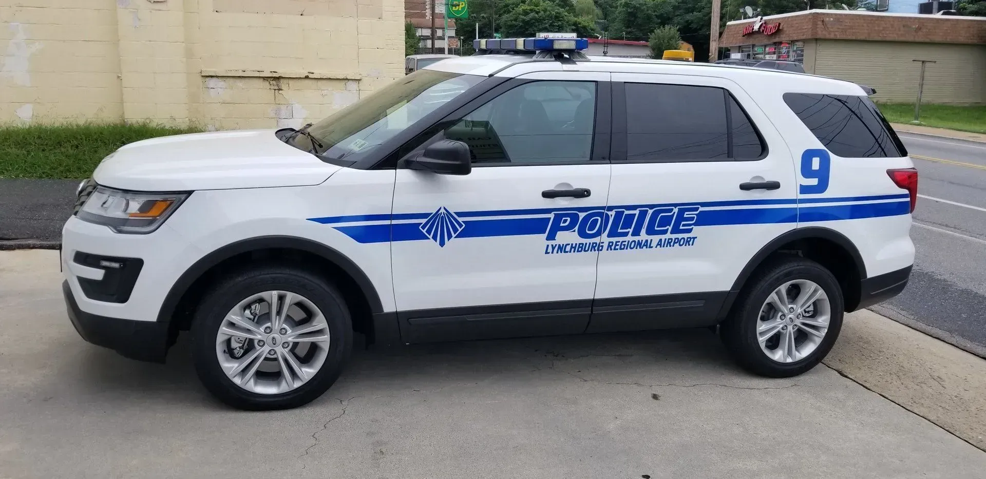A white and blue police car is parked on the side of the road.