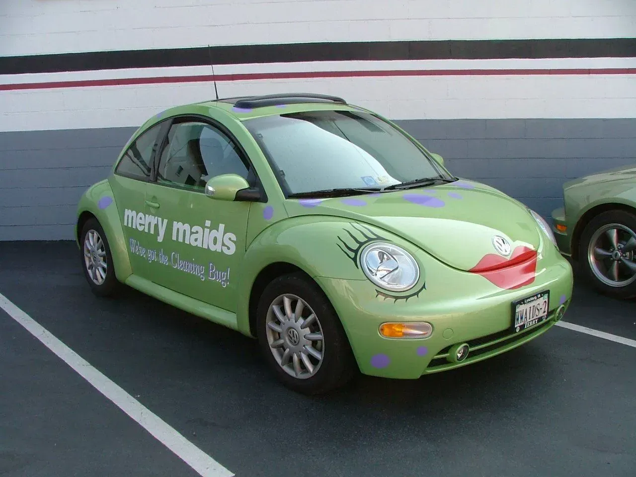 A green car that says merry maids on it.