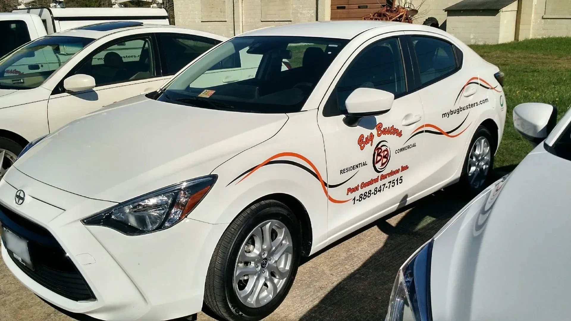 A white car with a red logo on the side is parked next to another white car.