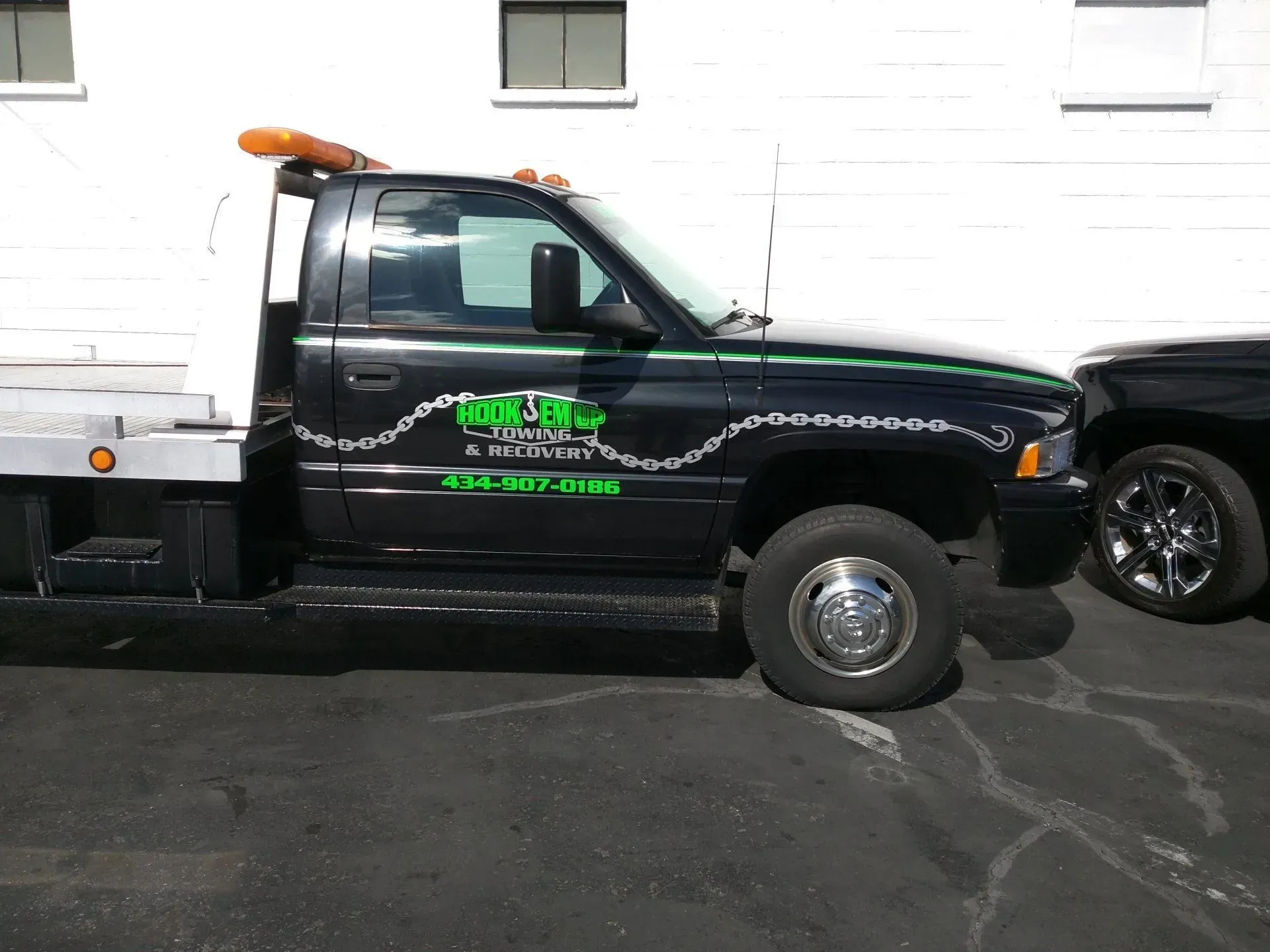 A black and white tow truck is parked in a parking lot.