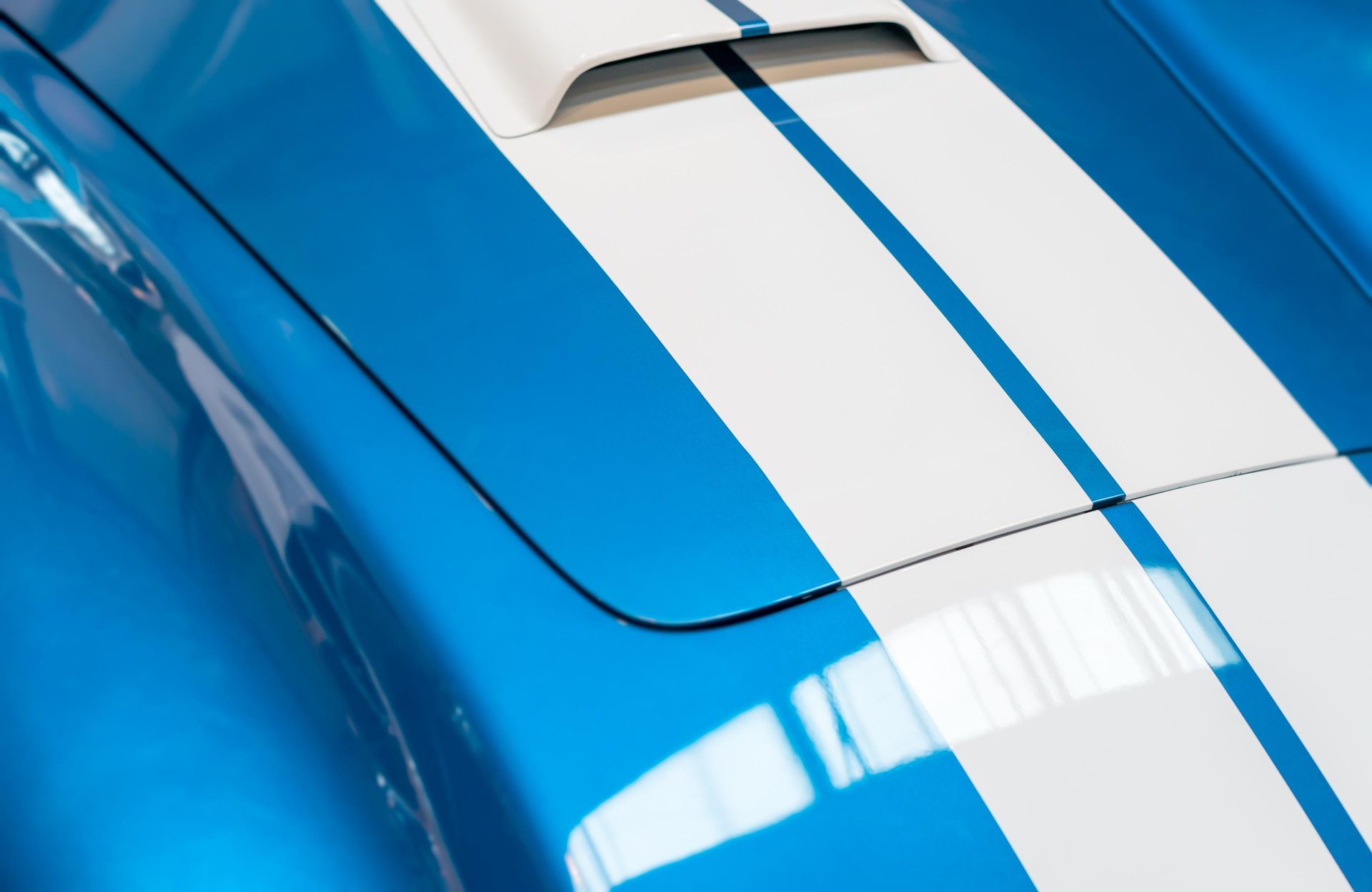 A close up of a blue car with white stripes.