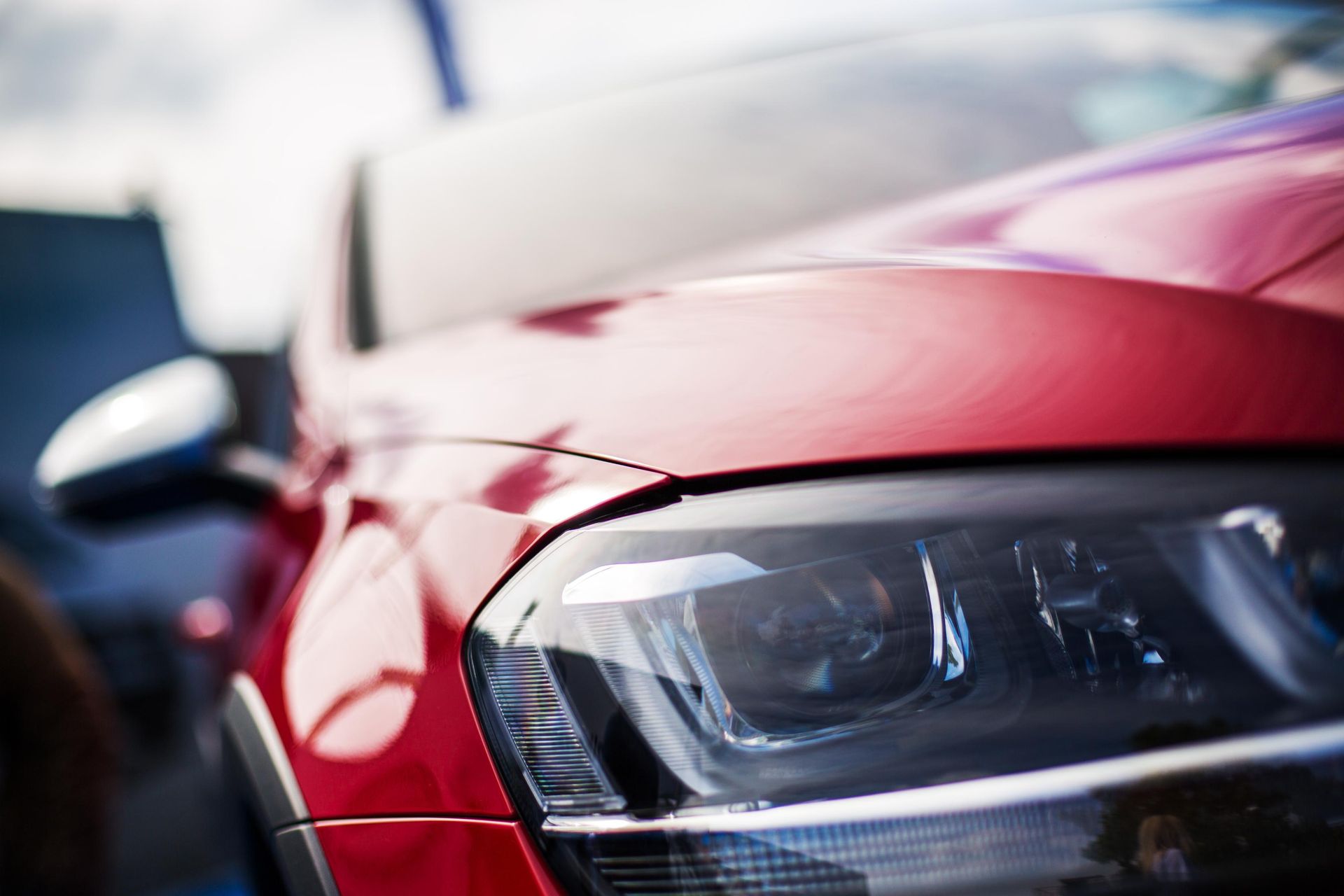 A close up of a red car 's headlight in a parking lot.