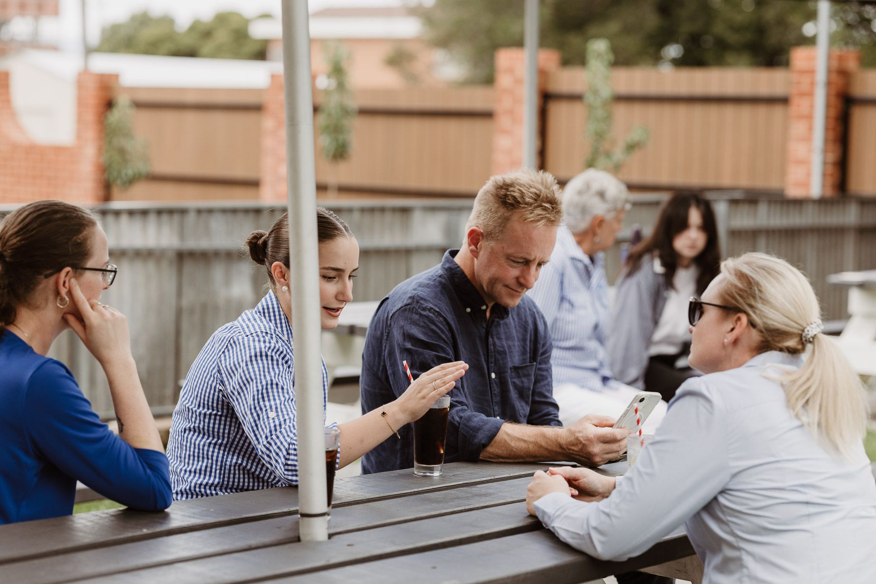 People gathered around an outdoor table talking and working together in a courtyard