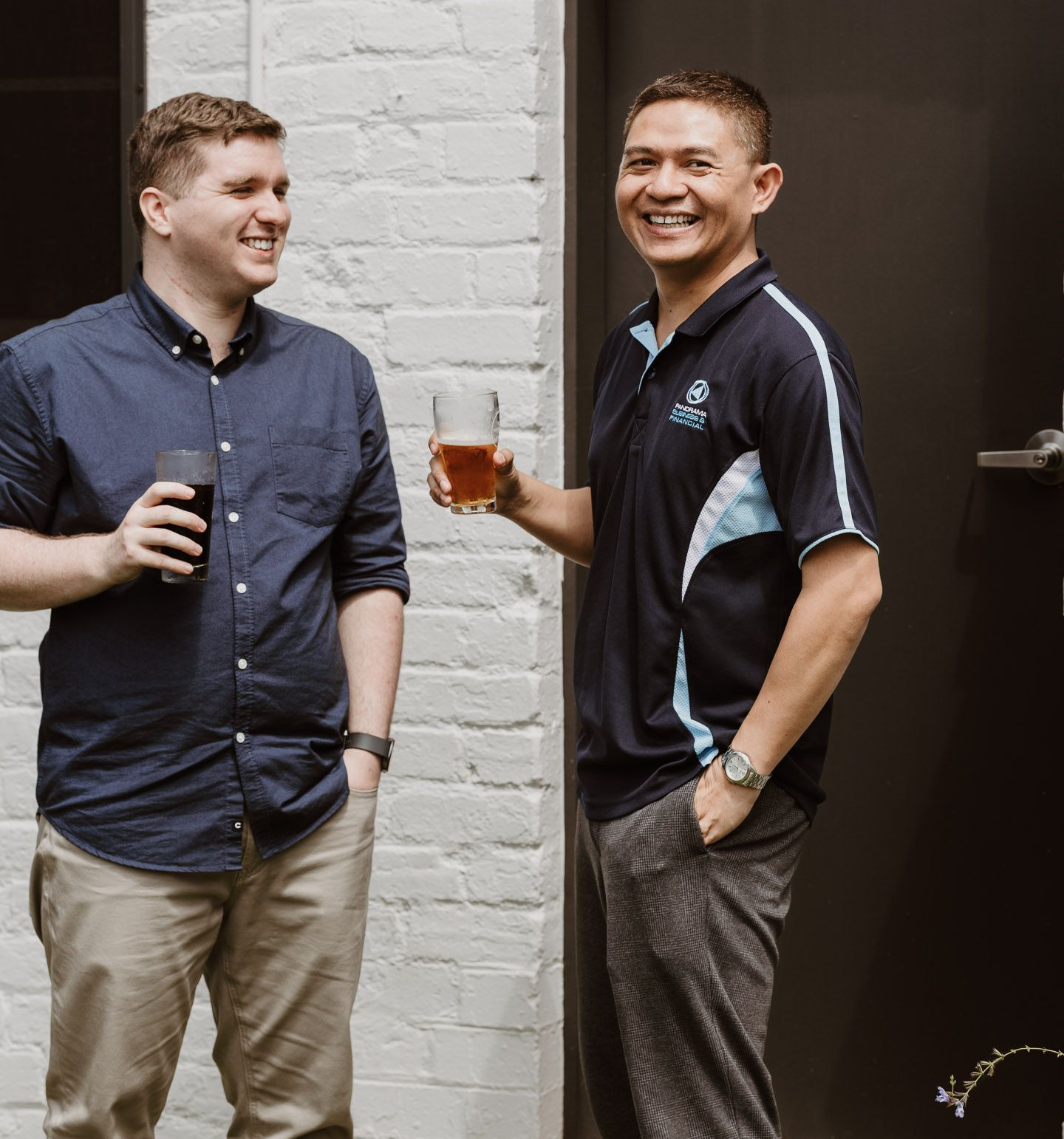 Group of people chatting outdoors, including one in a blue patterned shirt, in a bright garden setting