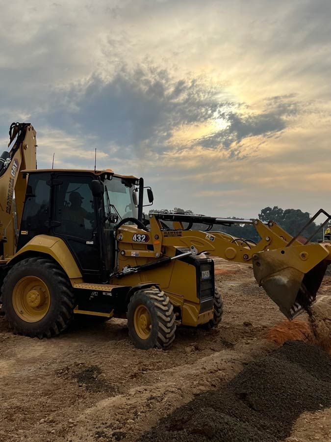 A Bulldozer is Digging a hole in the dirt on a Construction site — Mawson Constructions in Kialla, VIC